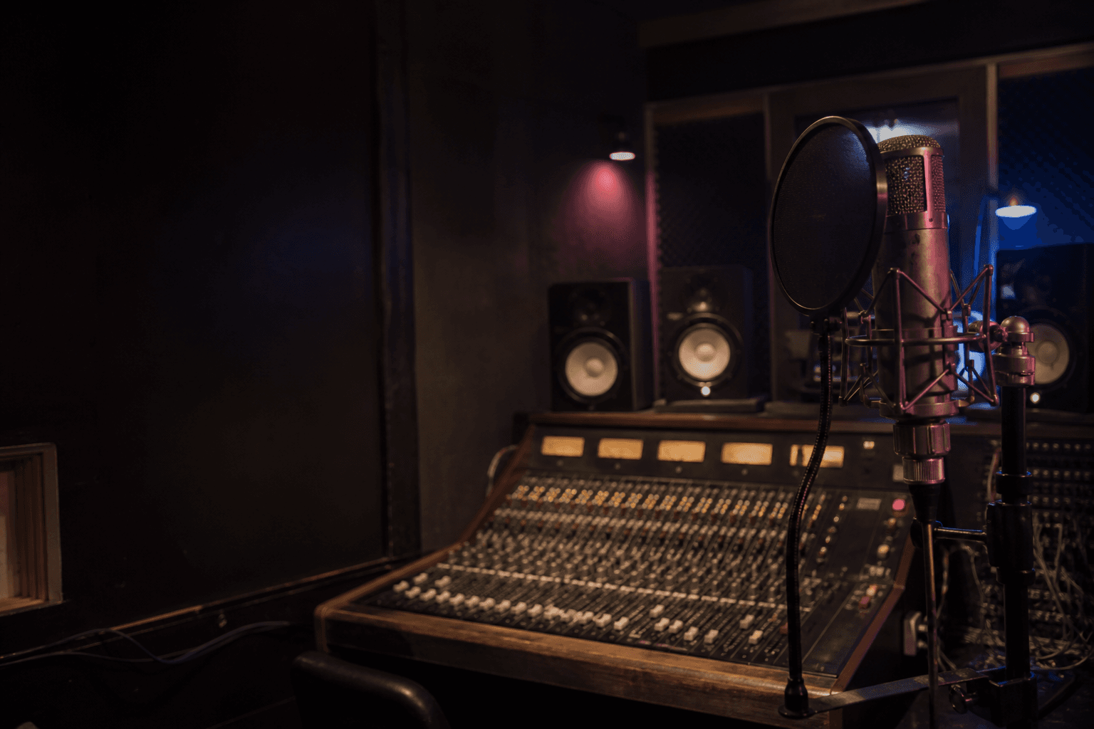 Vintage vocal microphone in a dark Deep Dripz-style recording booth, lit with deep blue and magenta practical light