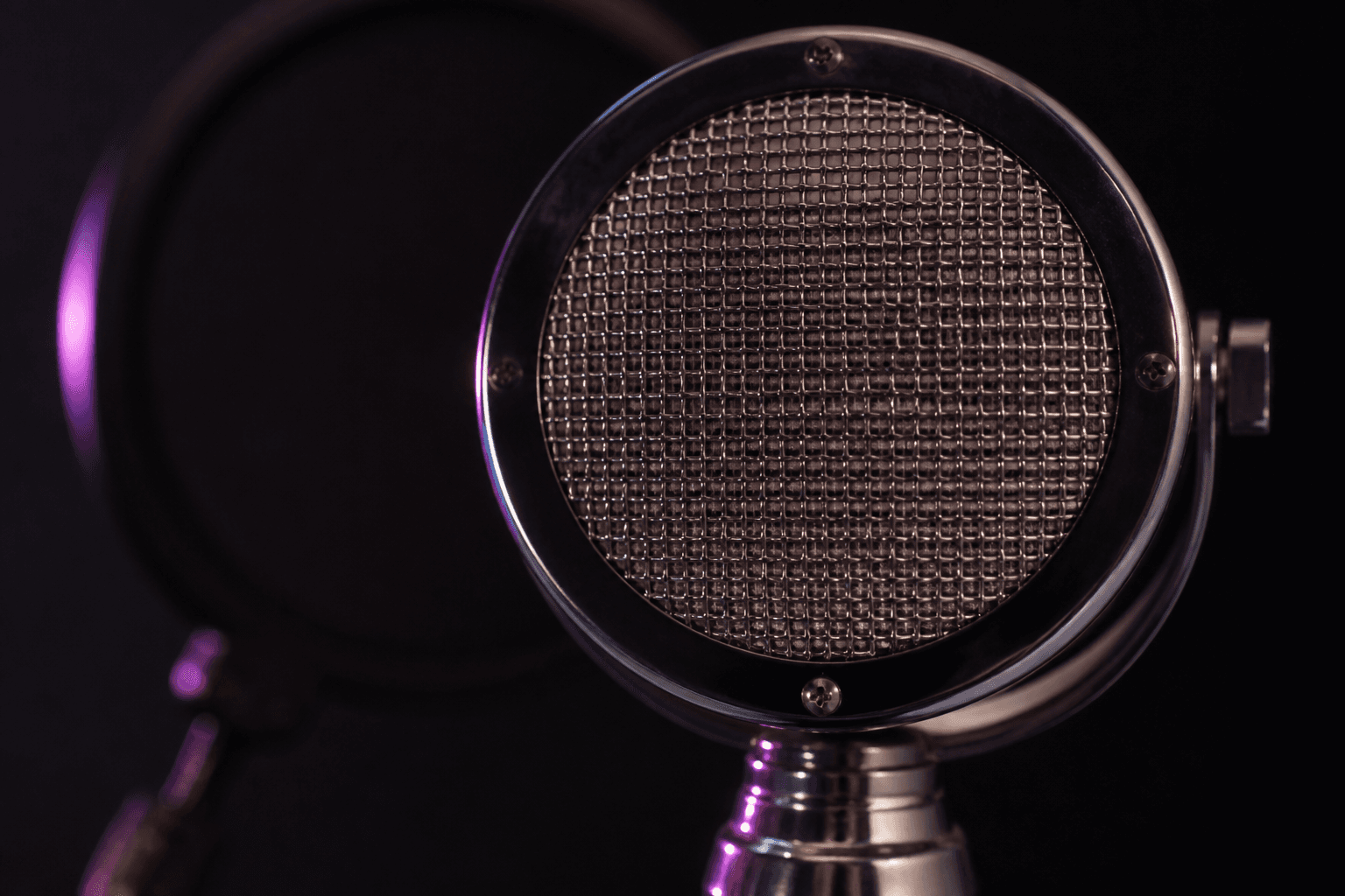 Close-up of a vintage vocal microphone in magenta studio light