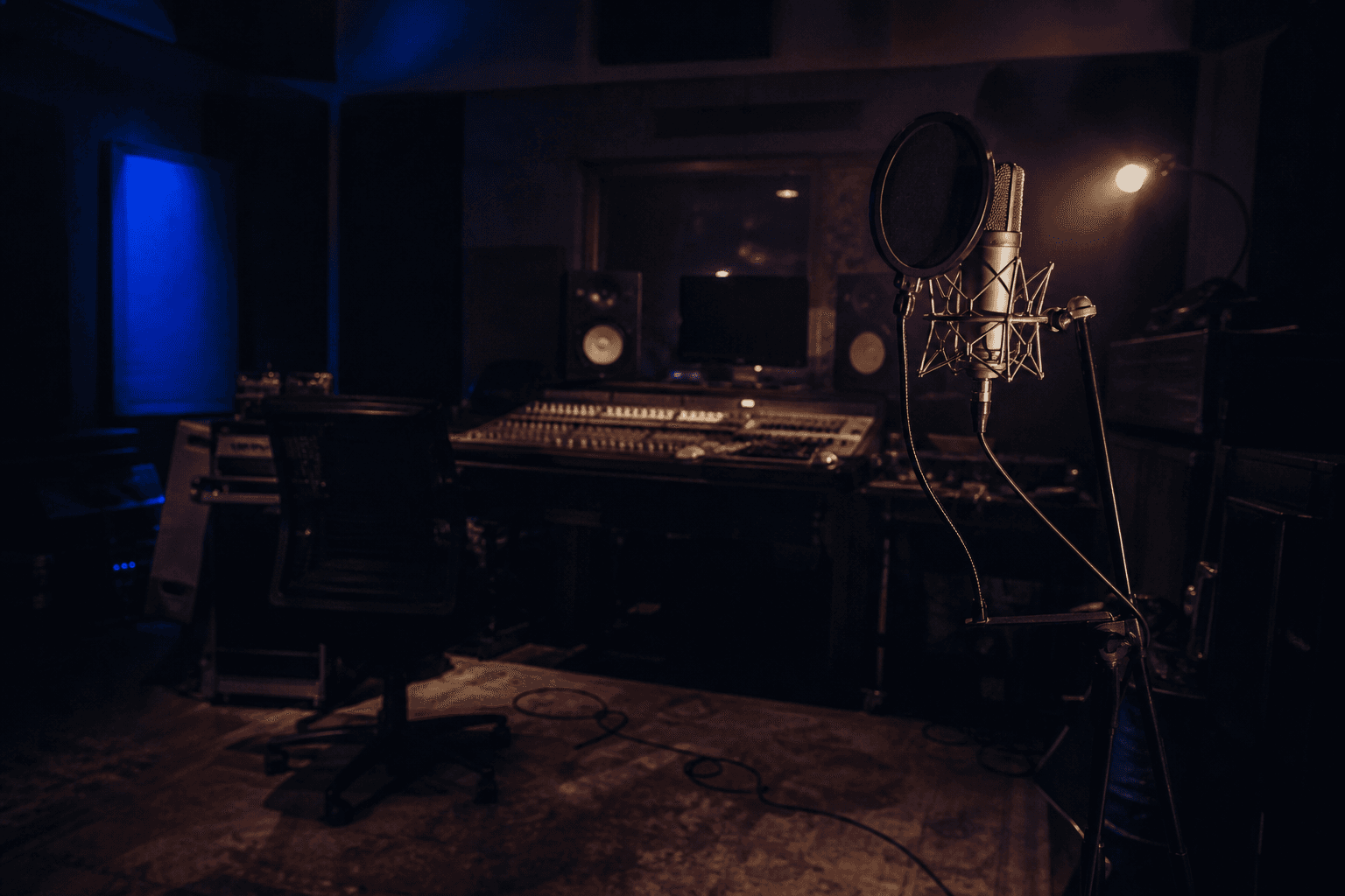 Empty recording studio after hours, microphone and desk still lit